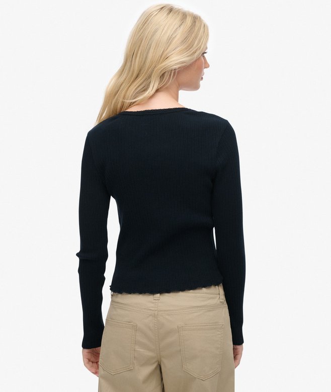 Woman wearing a navy sweater and beige pants on a white background
