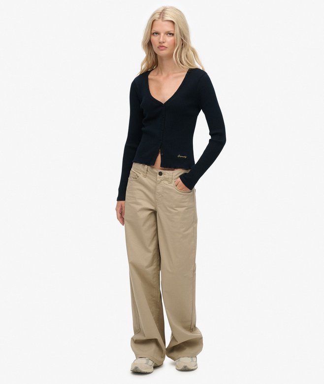 Woman wearing a navy top and beige pants on a white background
