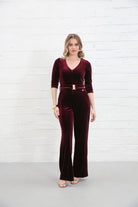 Rant & Rave Farrah Jumpsuit in wine velvet, front view worn by model with V-neck, zip front, gold belt and flared legs