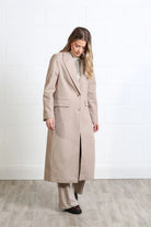 Rant & Rave Olivia Coat in biscuit, full - length front view worn by a model with a striped shirt and wide - leg trousers