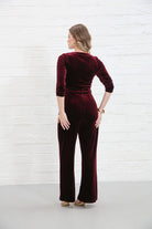 Rant & Rave Farrah Jumpsuit in wine velvet, back view worn by model showing rear seams and flared leg silhouette