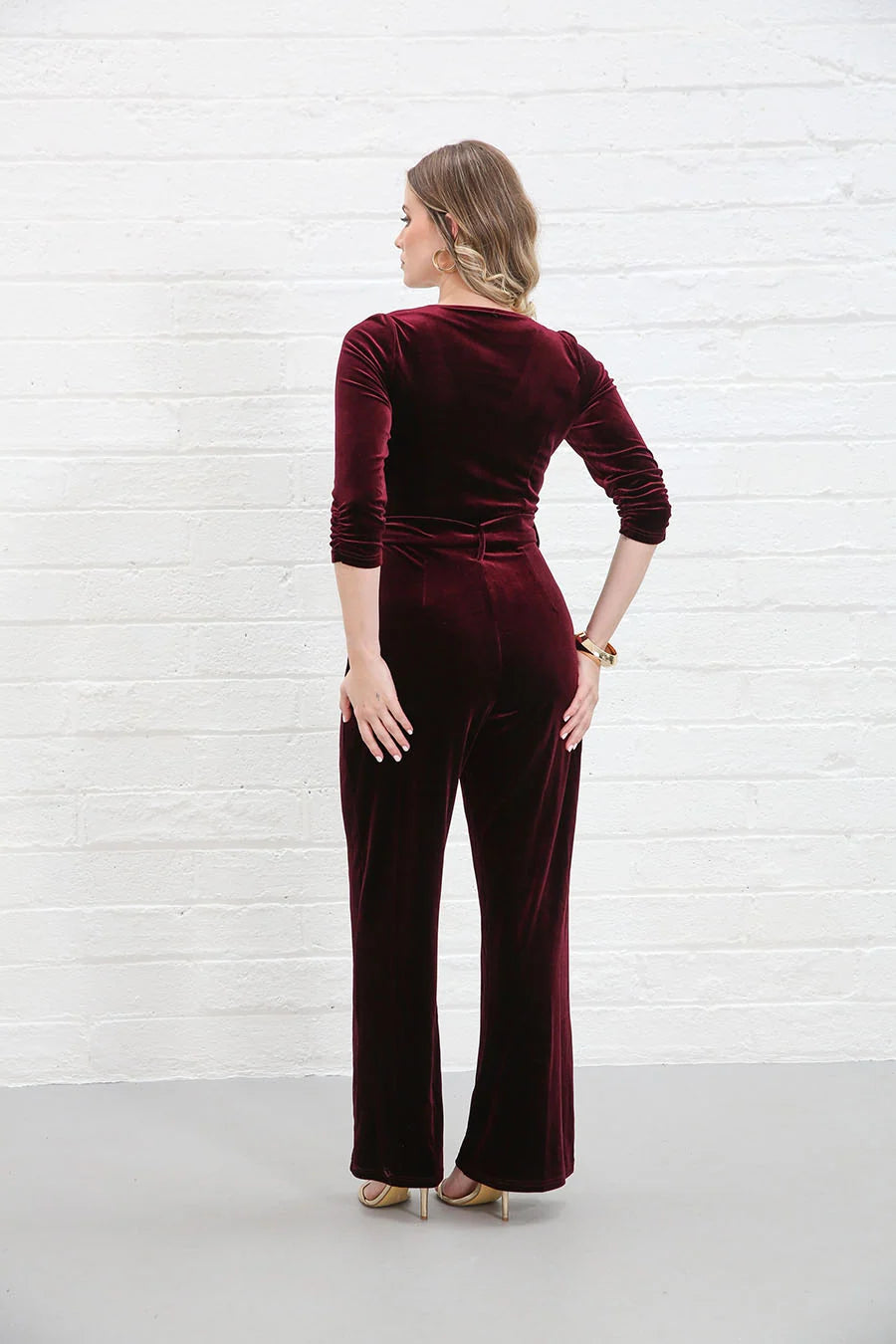 Rant & Rave Farrah Jumpsuit in wine velvet, back view worn by model showing rear seams and flared leg silhouette