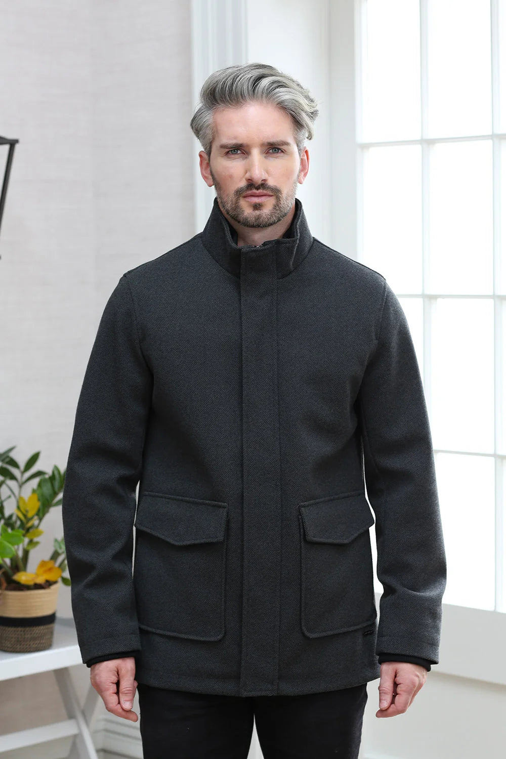 Kenrow Huxley Coat in charcoal worn by a male model, front view with coat closed, high funnel neck and two flap pockets visible.