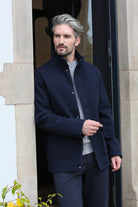Kenrow Huxley Coat in navy worn by a model in an angled front view, styled over grey trousers