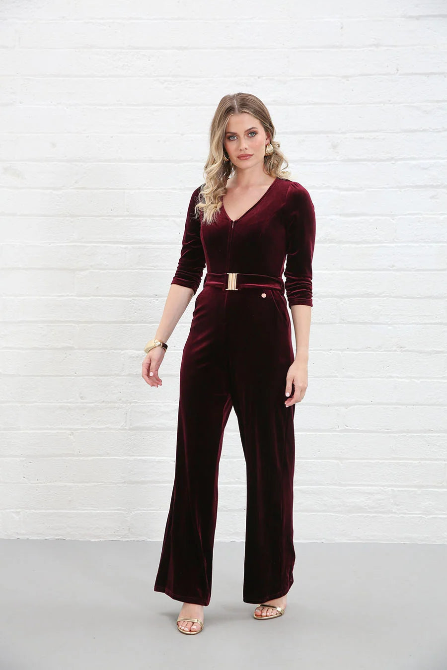 Rant & Rave Farrah Jumpsuit in wine velvet, angled front view worn by model highlighting gold belt and pocket detail