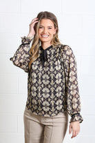 Rant & Rave Maria Top in gold, front model view with long sleeves and black tie neck detail
