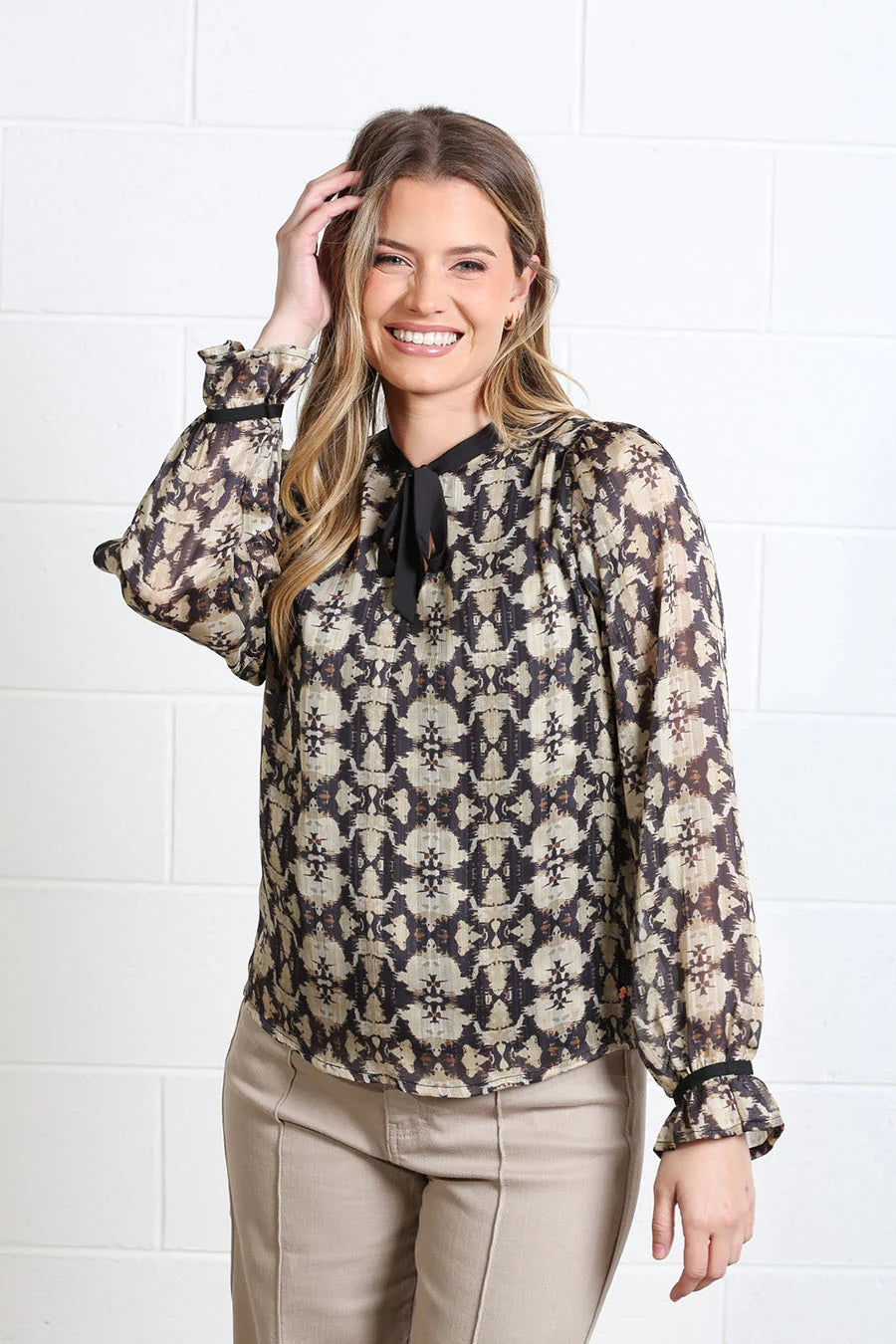 Rant & Rave Maria Top in gold, front model view with long sleeves and black tie neck detail