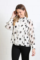 Rant & Rave Posy blouse in white, angled model view with black spot print and scalloped trim.