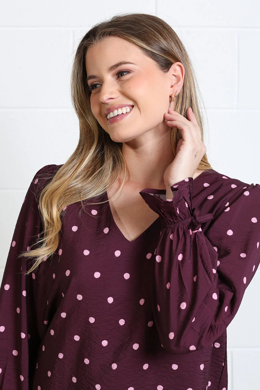 Rant & Rave Sophia top in burgundy dot with V-neck and long sleeves, close - up model view