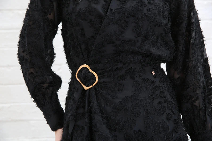 Detail view of the Rant & Rave Susannah Wrap Dress in black showing the gold buckle belt and textured floral fabric