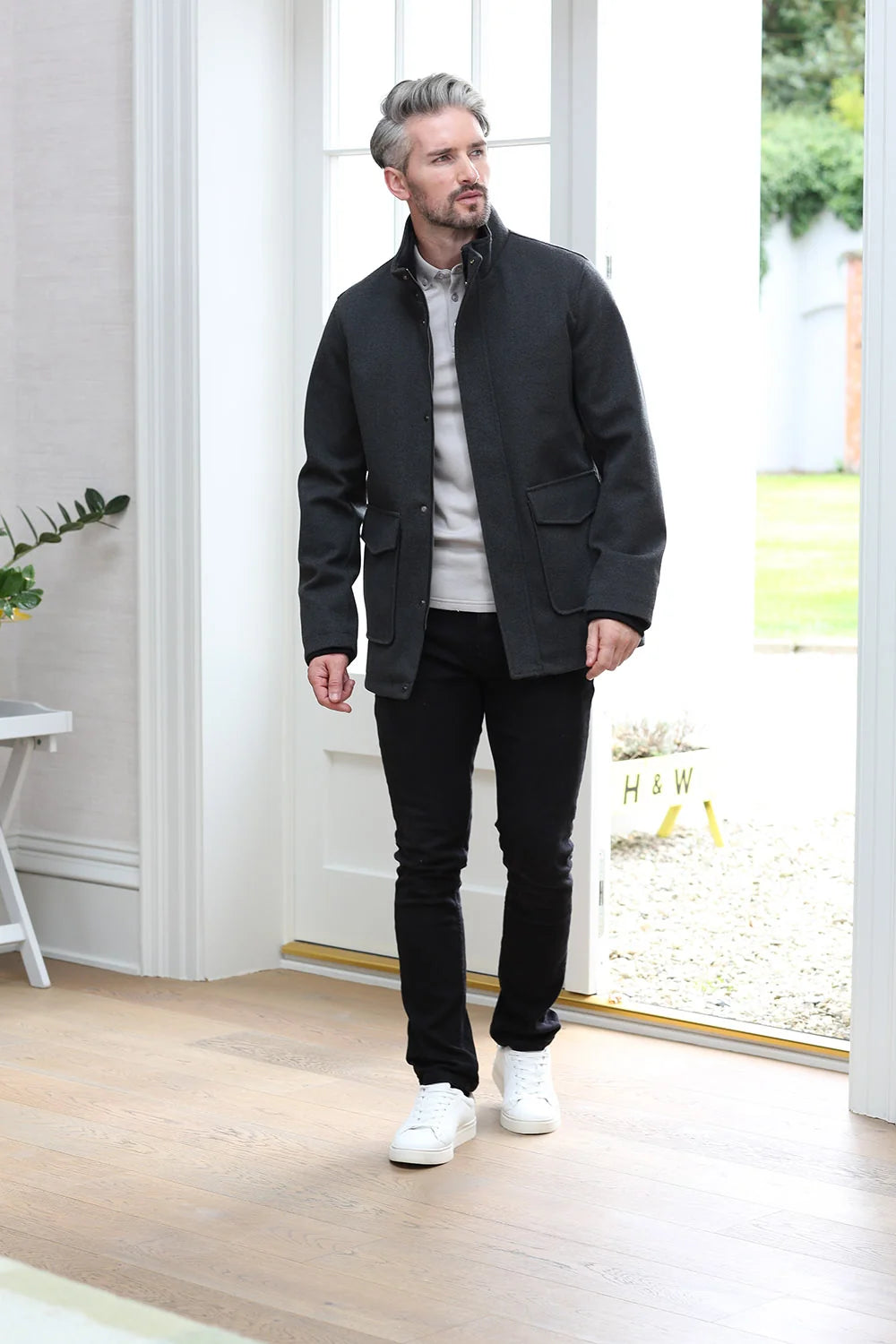 Kenrow Huxley Coat in charcoal worn by a male model, side profile view with coat open, high funnel neck and flap pocket visible.