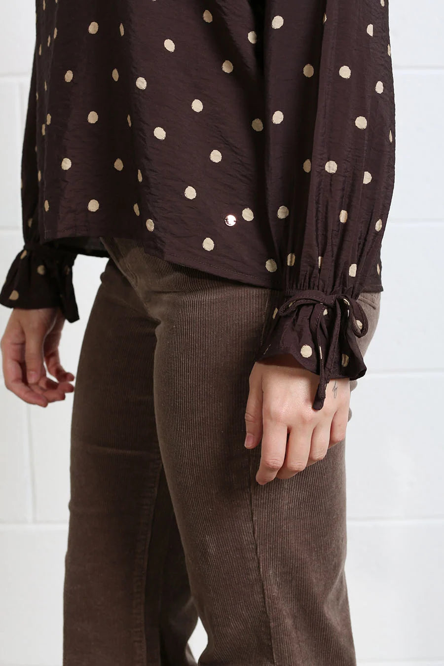 Detail view of Rant & Rave Sophia Top chocolate dot fabric with gold spots and tied cuff.