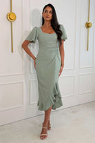 Girl In Mind Darcie sage frill midi dress worn by model, angled front view with asymmetric frill hem
