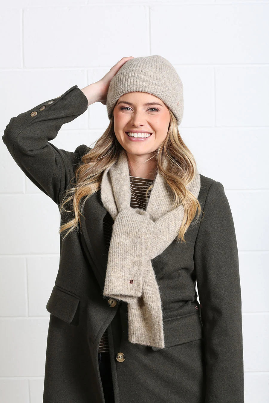 Rant & Rave Olivia Coat deep moss styled with beige scarf and beanie, smiling model close - up