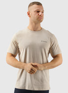 Man wearing a beige t-shirt with Columbia logo on a light gray background
