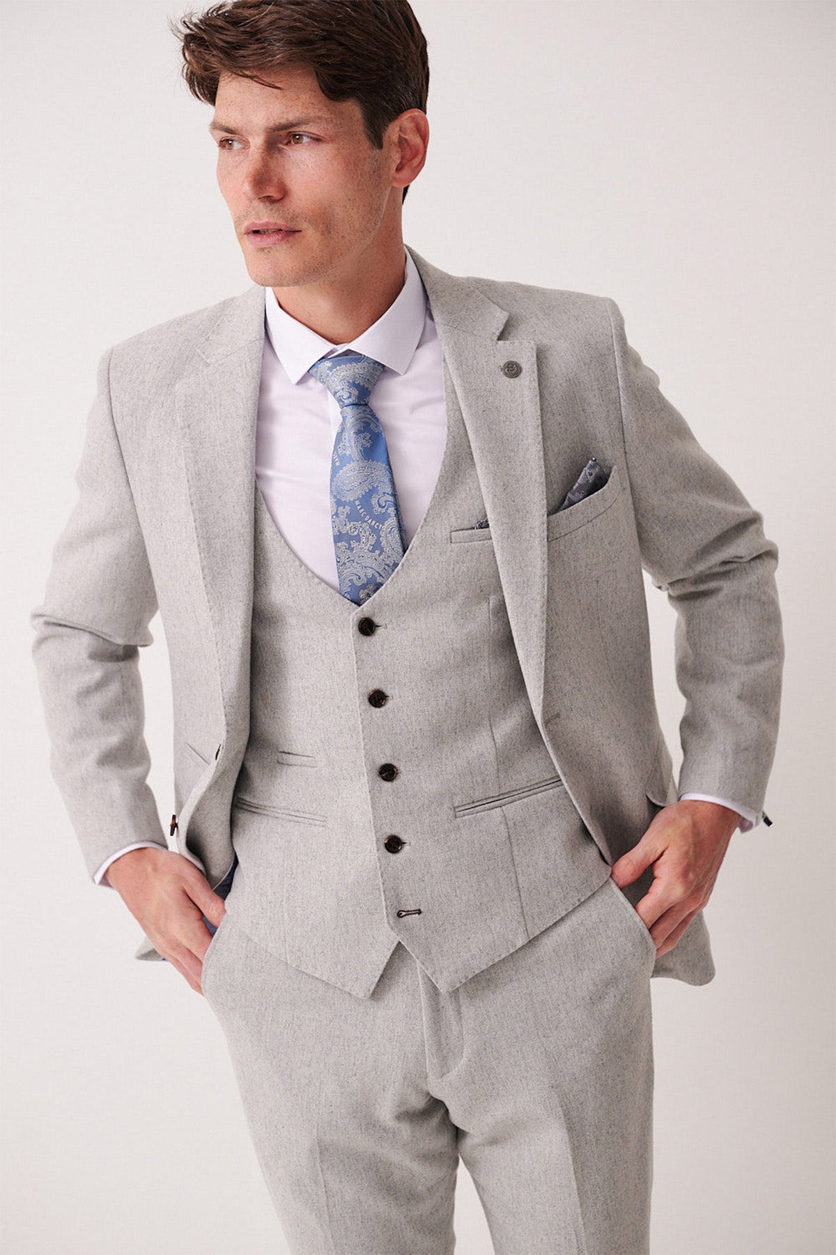 Man wearing a light gray suit with a white shirt and blue tie on a white background