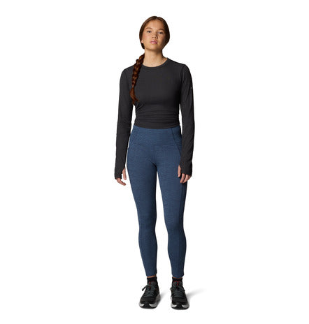 Person wearing a black long-sleeve top and blue leggings on a white background