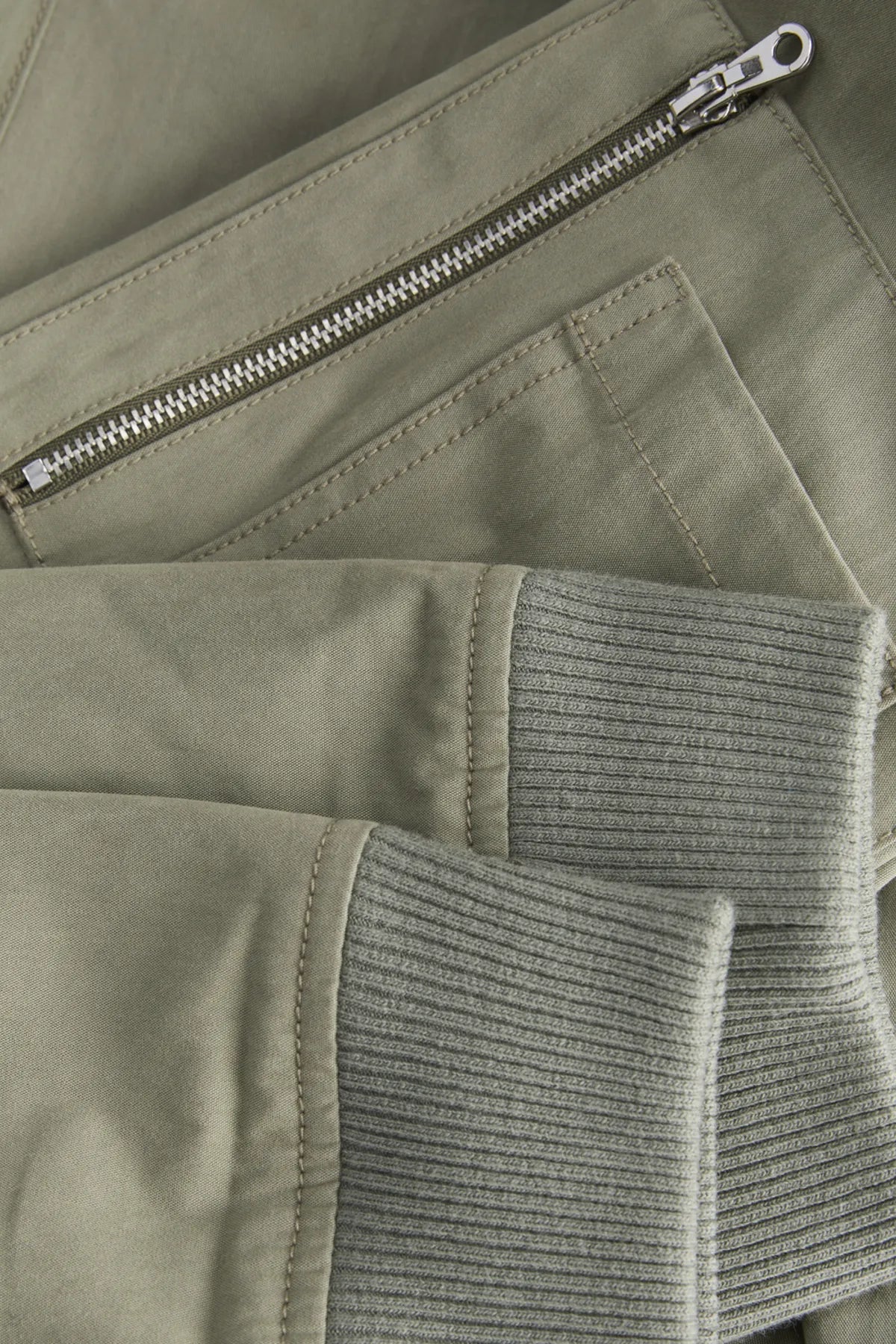 Close-up of a green jacket with a zipper and ribbed texture.