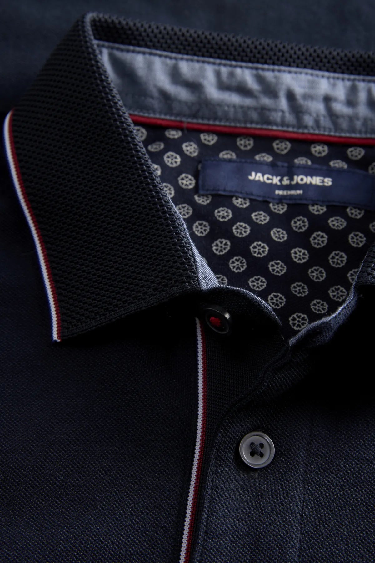 Close-up of a dark blue polo shirt with patterned collar and Jack & Jones branding.