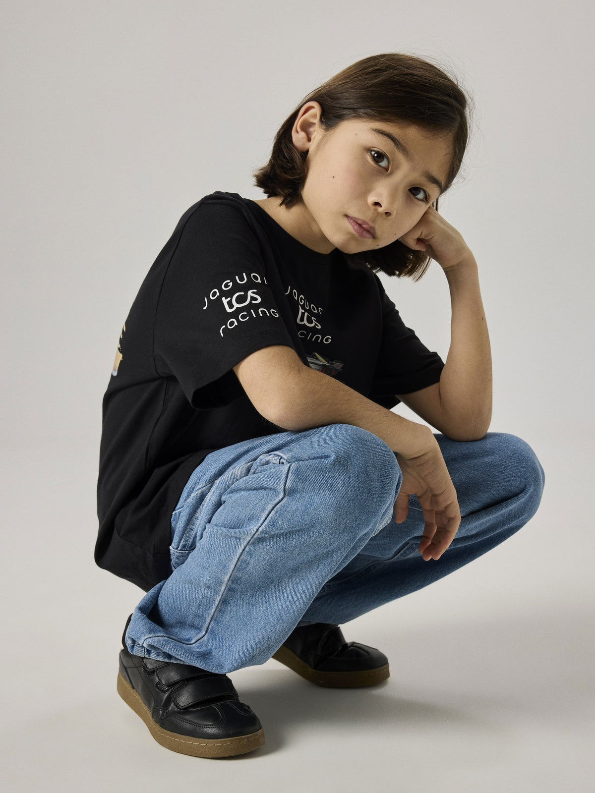 Seated model wearing the black NAME IT Alp Formula E racing T-shirt