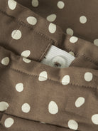 Close-up of the waistband button, elastic and dot print on NAME IT Rammie sweatpants in Coca Mocha