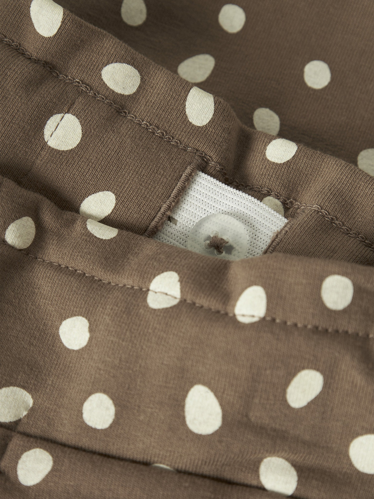Close-up of the waistband button, elastic and dot print on NAME IT Rammie sweatpants in Coca Mocha