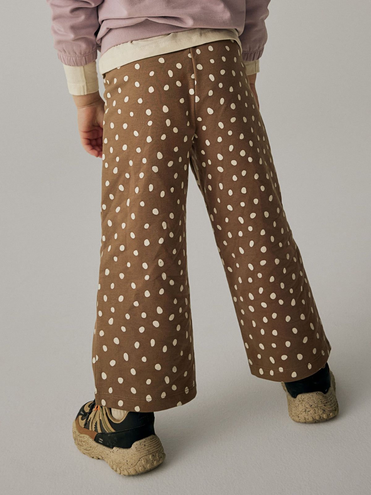 Close view of the back of NAME IT Rammie wide-leg dot-print sweatpants in Coca Mocha on a model