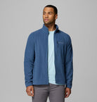 Man wearing a blue fleece jacket with a visible brand logo on a gray background