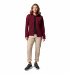 Woman wearing a burgundy fleece jacket with a hood on a white background