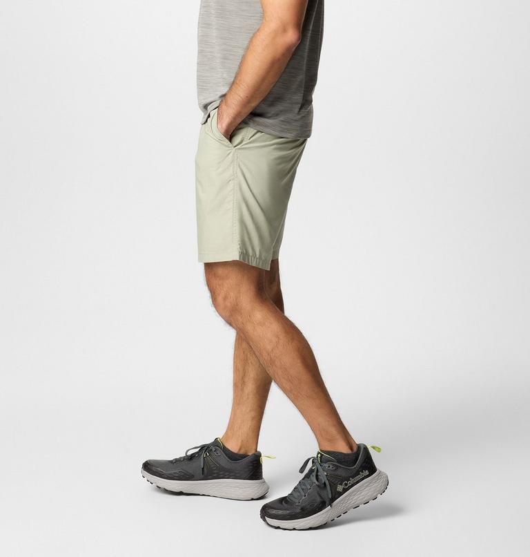 Person wearing light green shorts and dark gray sneakers on a white background