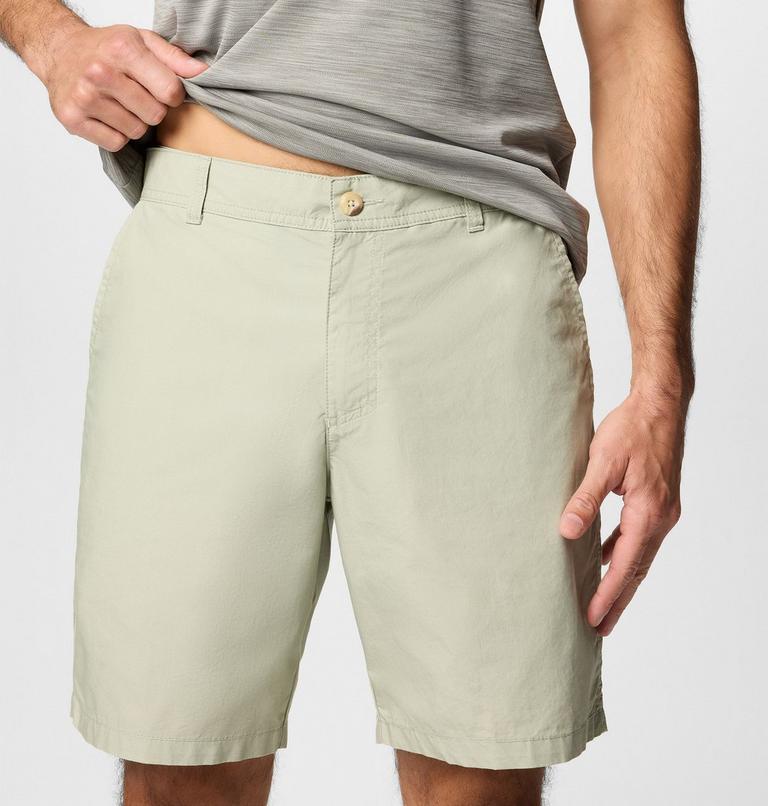 Person wearing light green shorts and a gray shirt on a plain background