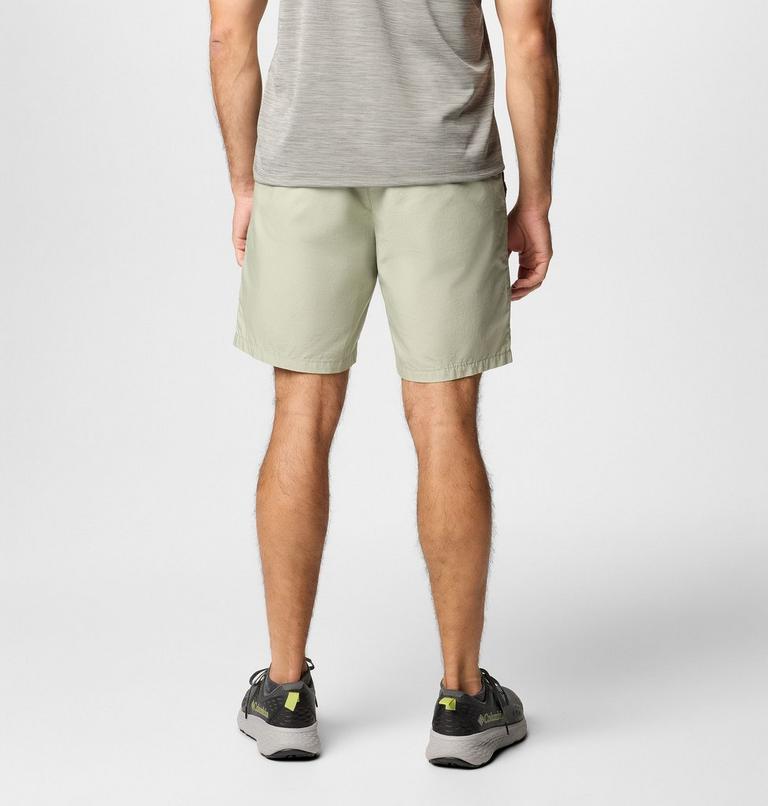 Person wearing beige shorts and gray shoes on a white background