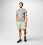 Man wearing a gray t-shirt and beige shorts on a white background
