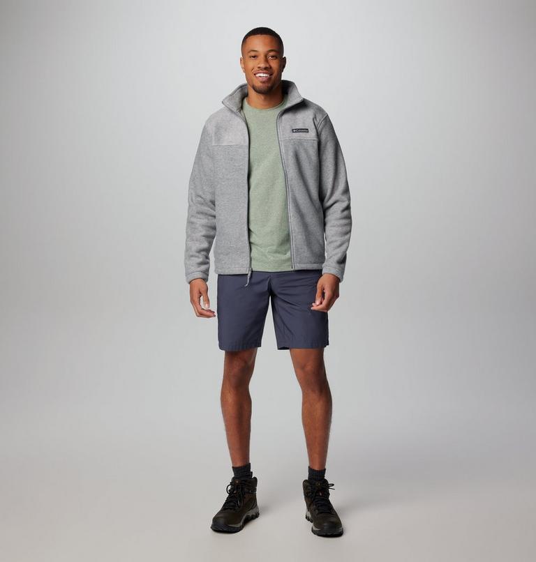 Man wearing a gray fleece jacket, green shirt, and dark shorts on a white background