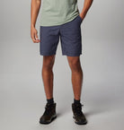 Person wearing navy shorts and hiking boots on a plain background