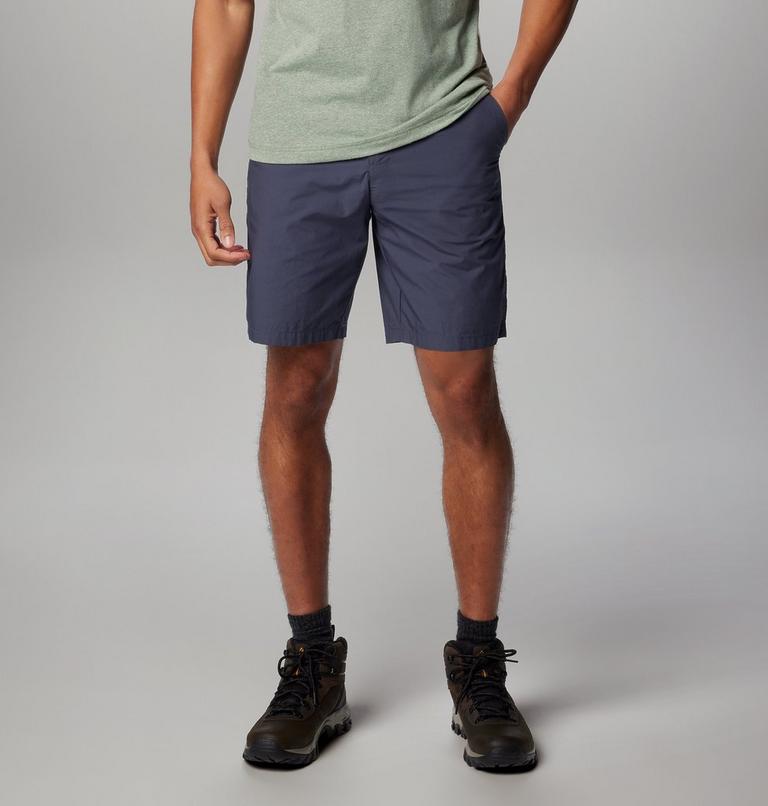 Person wearing navy shorts and hiking boots on a plain background