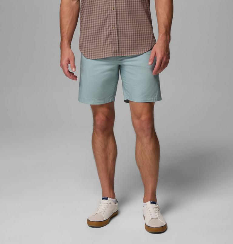 Person wearing light blue shorts and a plaid shirt on a gray background