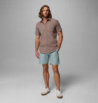 Man wearing a checkered shirt and light blue shorts on a gray background