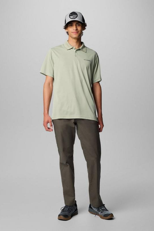 Person wearing a light green polo shirt and dark pants on a gray background
