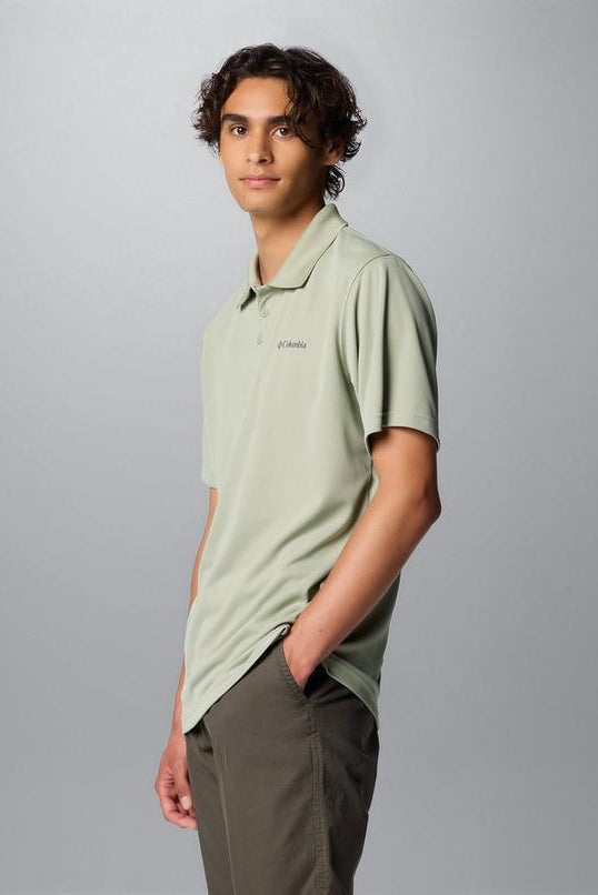 Person wearing a light green polo shirt with a brand logo on a gray background