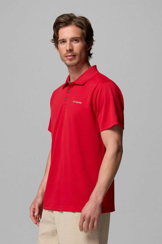Man wearing a red polo shirt with a logo on a gray background