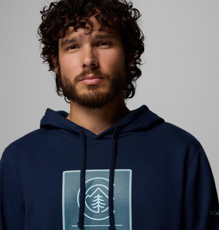 Man wearing a navy blue hoodie with a logo on a gray background