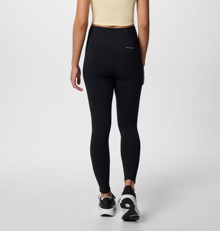 Person wearing black leggings with a visible brand logo on a light gray background