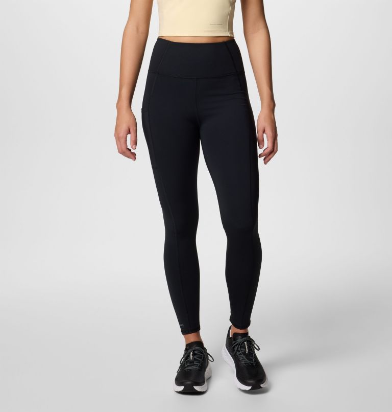 Person wearing black leggings and a beige top on a light gray background