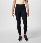 Person wearing black leggings and a beige top on a light gray background