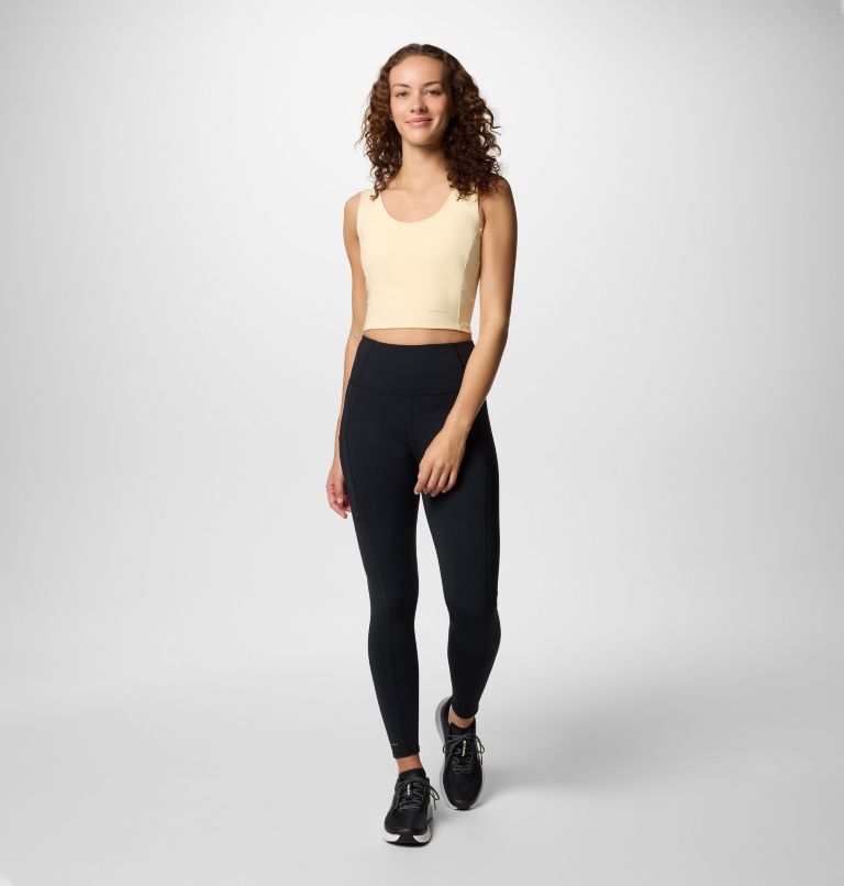 Woman wearing a yellow tank top and black leggings on a white background