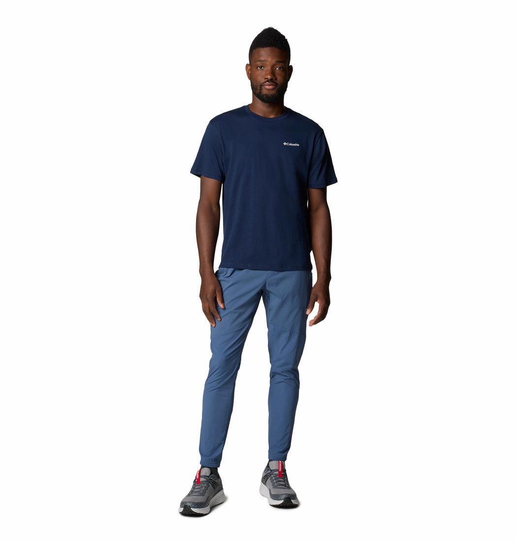 Man wearing a navy t-shirt and blue pants on a white background