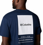 Navy blue t-shirt with Columbia logo and text on the back, worn by a person.