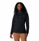 Woman wearing a black fleece pullover with a visible brand logo on a white background