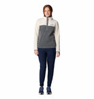 Woman wearing a two-tone pullover and dark pants on a white background